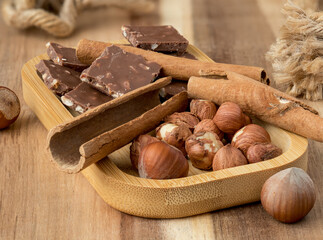 Hazelnuts, cinnamon, chocolate with nuts, background, Christmas wallpaper on a wooden countertop, close-up view, healthy unsaturated fats, spices, plant protein, fiber, vitamins and minerals