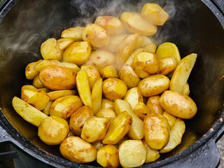Cooking fresh potatoes in a large pot over an open flame at an outdoor gathering