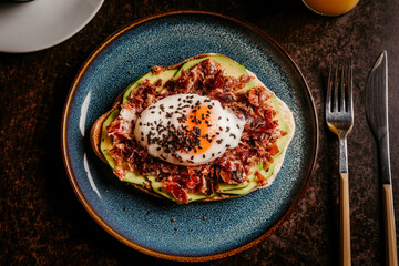 Gourmet toast  with grated cheese, avocado, ham, grated cheese and fresh herbs. Warm mood lighting perfect for Italian cuisine projects and cooking articles.