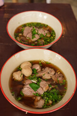 The closed up of Thai noodles. Asian noodle soup with beef meatball with fresh vegetable on wood table. 