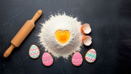 Easter decorations: gingerbread in the form of Easter eggs, fresh flour with a broken raw egg in the shape of a heart. We are preparing for Easter, cooking cakes