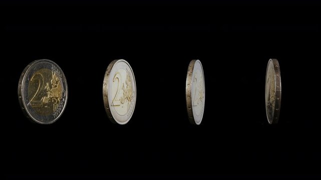 Lots  of the two euro coins spin  around their  axis  on black background.