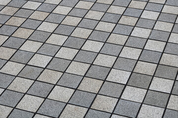 A geometric pattern of square speckled tiles laid diagonally in a classic checkerboard arrangement.