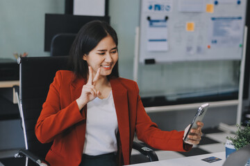Serious charming woman using smartphone while working with laptop