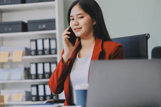 Serious charming woman using smartphone while working with laptop - Powered by Adobe