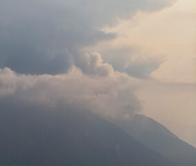 Dark clouds gather over mountain peaks at sunset, creating a peaceful and dramatic landscape