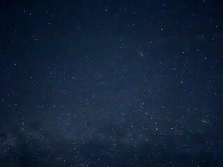 Countless stars twinkle brightly in the dark night sky over a tranquil setting