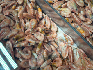 Vendors display fresh shrimp at a bustling morning market, attracting eager shoppers