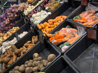 Colorful vegetables, including fresh carrots and beets, are neatly arranged in a market