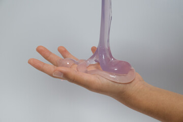 Purple slime pouring from a container onto a hand