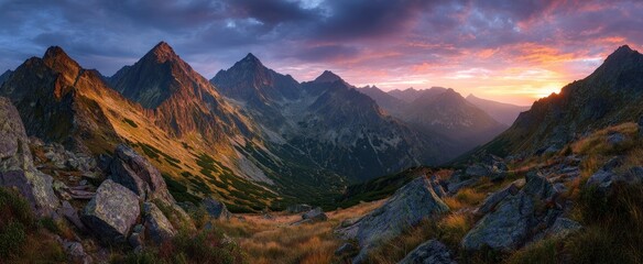 Mountain valley landscape at sunrise with dramatic colorful sky and rugged terrain.