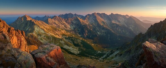 Obraz premium Rugged mountain range illuminated by warm sunrise or sunset light.