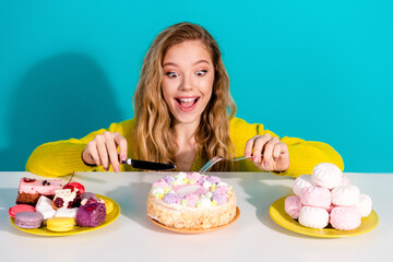 Young woman in a yellow sweater joyfully enjoys a colorful cake and pastries in a bright blue...