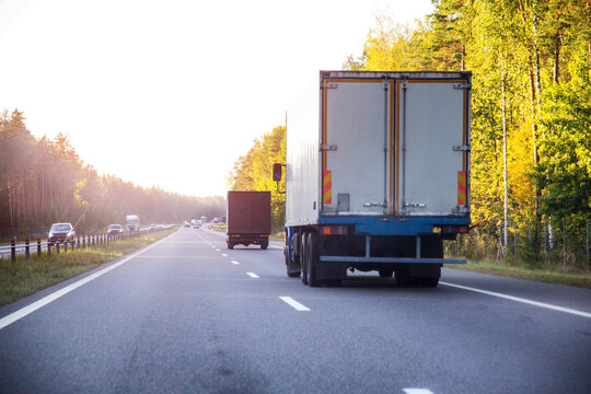 Fototapeta A refrigerated truck transports perishable food cargo along a highway in summer against a sunset backdrop, industry. Copy space for text