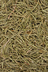 A close-up, high-angle texture shot of dried, needle-like rosemary leaves and small stems