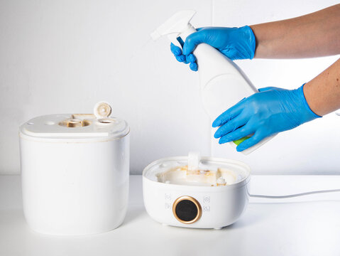 Spraying a chemical rust and scale remover into a humidifier. Home humidifier maintenance, close-up. Copy space for text