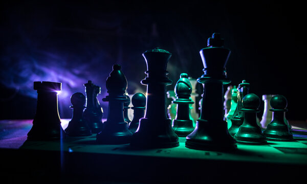 Chess board game concept of business ideas and competition. Chess figures on a dark background with smoke and fog.