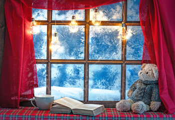 christmas cozy interior background with window sill illuminated with lights and bear toy