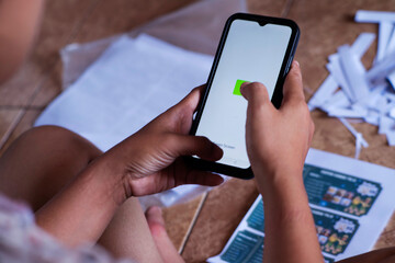 Girl Using Smartphone with Papers Spread on the Floor