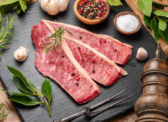 Sliced picanha beef with spices and herbs on a gray stone serving board top view. Traditional Portuguese food.