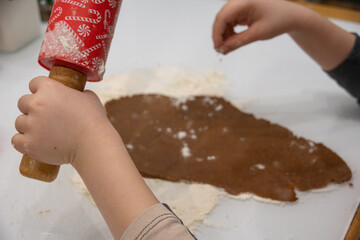 Little child rolling raw dough at white table, Christmas preparation
