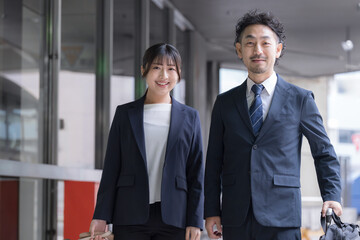 Fototapeta premium ビジネス出張でスーツケースを引く会社員の笑顔の移動シーン カメラ目線笑顔