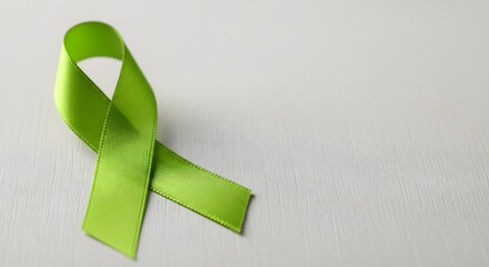Green mental health awareness ribbon on a white textured background for support and advocacy concept with ample copy space
