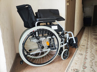 Manual wheelchair indoors, modern design, black seat and backrest, silver frame, white tires, ready for use, medical equipment for mobility, aid for disability, comfortable seating