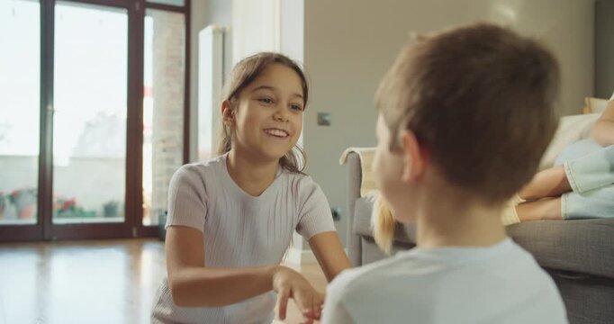 Children playing clapping game in cozy living space with adults and pet