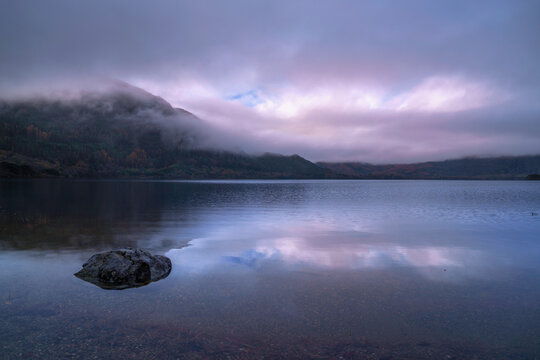Muckross Lake serene landscape on a winter morning after rain, with fogs and drifting clouds over Shehy Mountain in Killarney National Park, Ireland, a Zen‑like sunrise tranquility and relaxation.