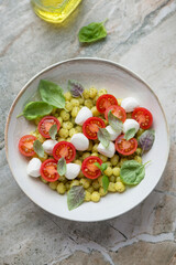 Plate of italian potato gnocchi with cherry tomatoes and mini mozzarella, vertical shot on a grey granite background, elevated view