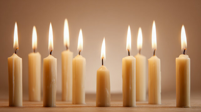 Softly glowing beige candles burning in a row against a neutral background creating a warm and peaceful atmosphere for meditation or relaxation settings