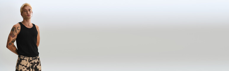 Handsome young man poses confidently, showcasing his unique style against a clean background.