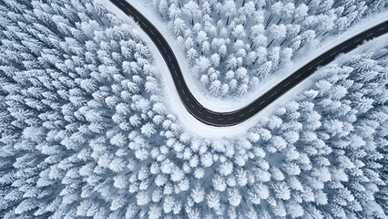 Stunning aerial view of winding road through snow-covered forest, a serene winter wonderland perfect for travel and adventure visuals