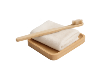 Bamboo toothbrush rests on folded white towel in wooden tray