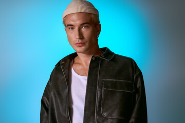 Handsome young man poses confidently, showing off trendy attire against a colorful backdrop.