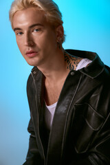 Handsome young man models a trendy outfit with a striking blue background, exuding confidence.