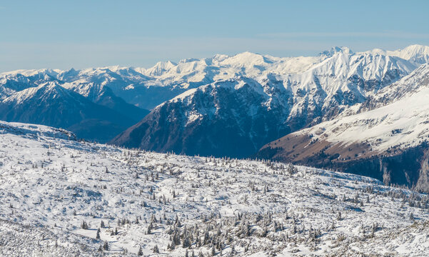 Snowy mountain landscape under a clear blue sky. Distant peaks are covered in snow. Paganella, Roda refuge, Trentino, Italy