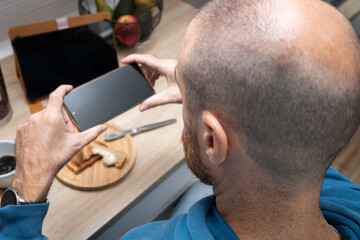Man taking a photo of breakfast with his phone