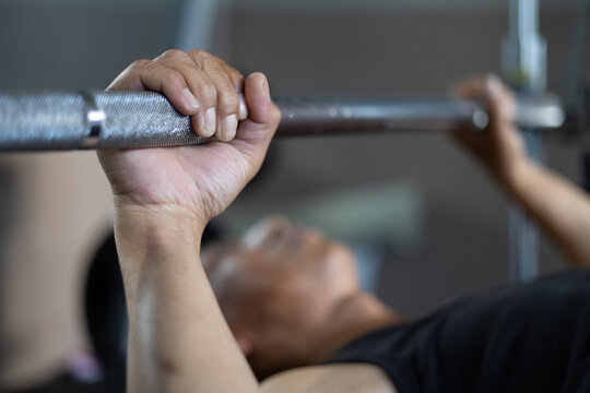 Close-up of a man’s hand gripping a barbell during bench press workout in the gym, control focused muscle training in a fitness lifestyle.