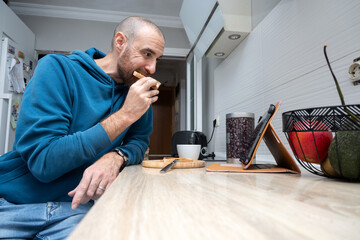 Man having toast for breakfast while using a tablet at home