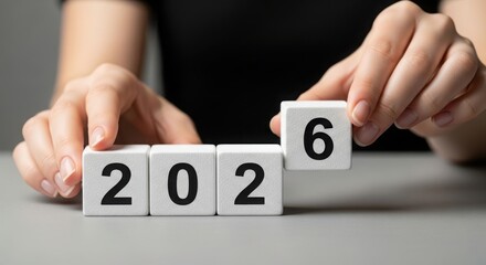 Hand places block to form year 2026