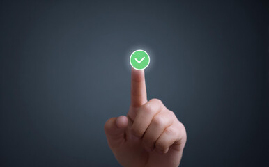 Finger touching virtual green checkmark button displaying success and approval on dark background with satisfaction and positive emotion showing complete correct finish