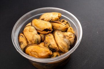 Pickled Mussels in Plastic Container on Dark Background