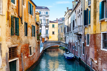 Beautiful view of colorful facades of old houses, canals and bridges in Venice, Italy.  Venice canal with docked boat, Italy.