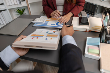 Business professionals reviewing financial charts and performance reports during a meeting, highlighting strategic planning, budget analysis, and teamwork in a modern corporate environment.