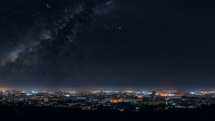 City skyline at night with the Milky Way visible in the dark sky