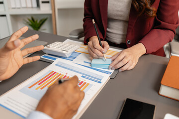 Business professionals meeting at a modern office table, reviewing charts and budget reports while discussing key financial insights and strategic plans for upcoming business decisions.