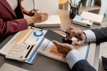 Business professionals meeting at a modern office table, reviewing charts and budget reports while discussing key financial insights and strategic plans for upcoming business decisions.