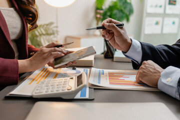 Business professionals meeting at a modern office table, reviewing charts and budget reports while discussing key financial insights and strategic plans for upcoming business decisions.